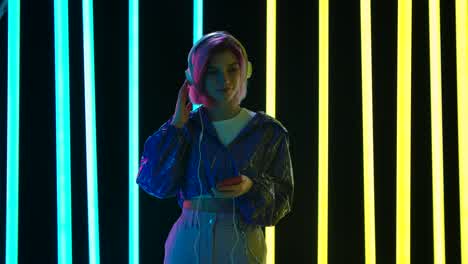 woman with headphones and phone in neon light