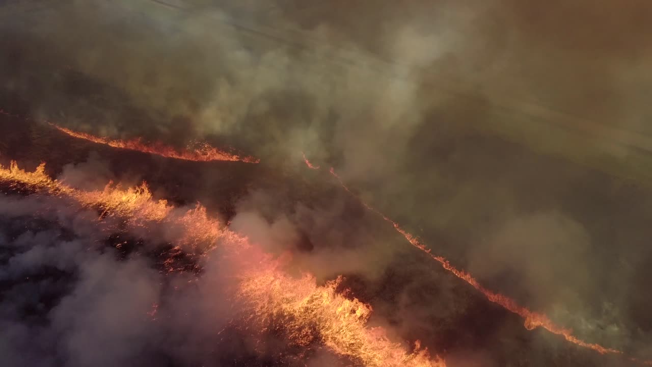 Flying over fire scorched earth field fire prairie burn