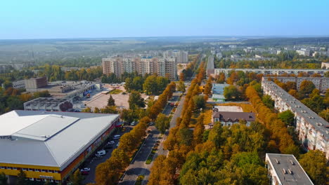 city scenery on autumn day from aerial perspective. drone footage over the multi-storied buildings and multiple trees.