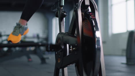 Portrait-Caucasian-woman-exercising-workout-on-stationary-cycling-machine-bike-in-gym,-slow-motion