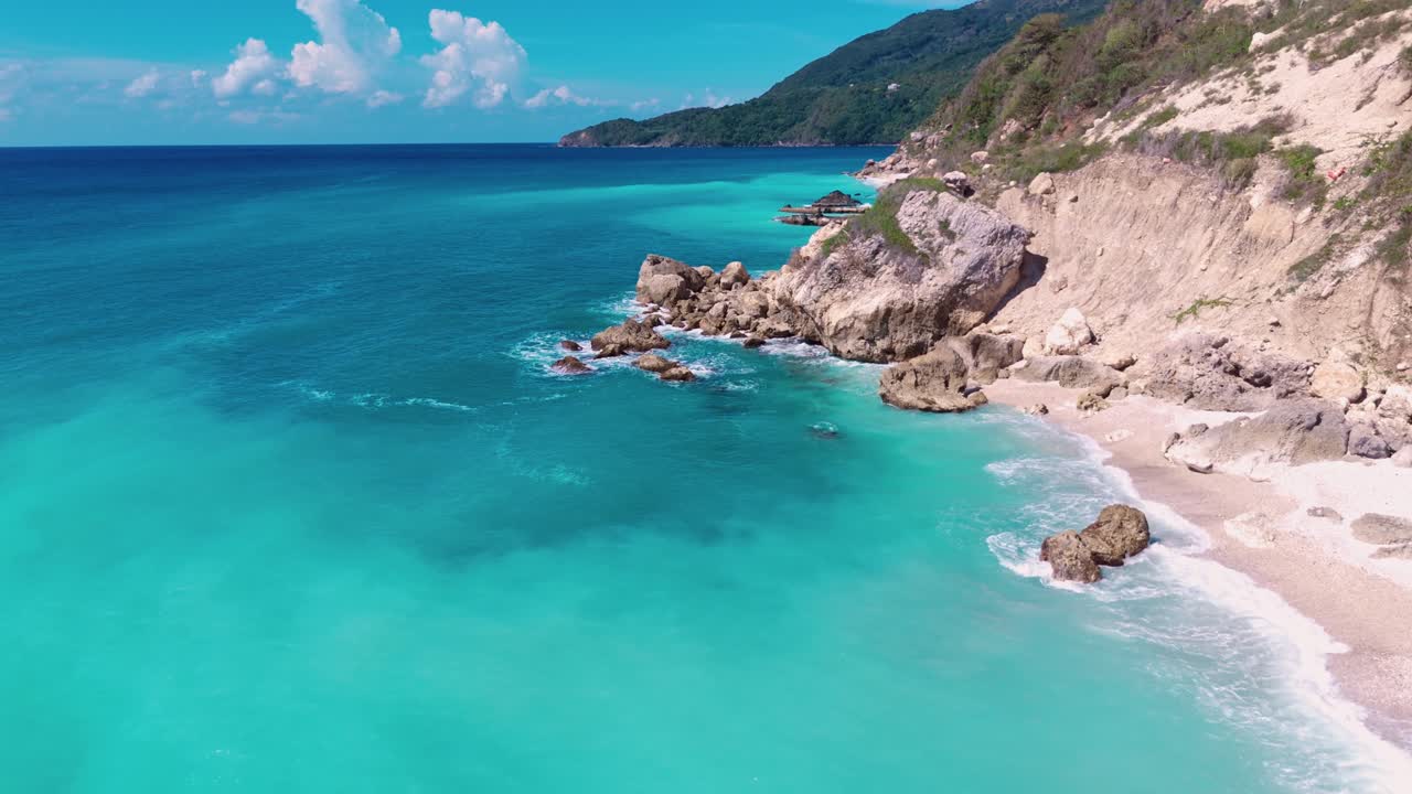 Empty Sandy beach or Barahona with turquoise clear water of Caribbean Sea at sunny day. Peaceful landscape coastline on Dominican Republic. Aerial forward wide shot