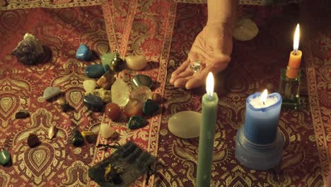 close-up shot of a mystical healer performing a ritual with magic gems and swinging the pendulum to read the future and the energy of the magic rocks