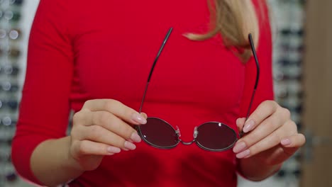 cute girl with new glasses in shop. young woman choosing sunglasses in store