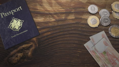 pasaporte de viaje con papel y monedas en mesa de madera