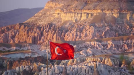 bandera turca ondeando en capadocia con el valle rojo al fondo
