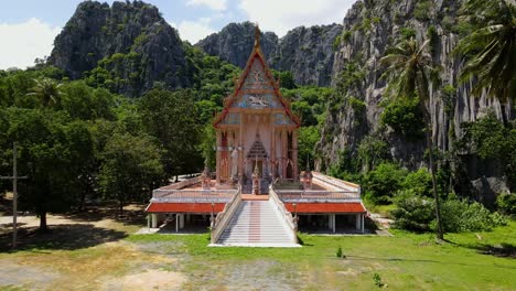 Eine-Stetige-Luftaufnahme-Dieses-Buddhistischen-Tempels-Inmitten-Der-Kalksteinberge,-Des-Waldes-Und-Der-Kokospalmen