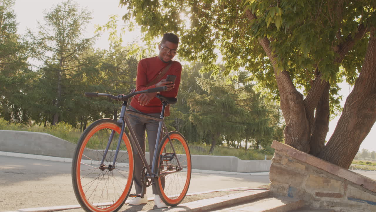 African American Man with Bike Using Smartphone Outdoors