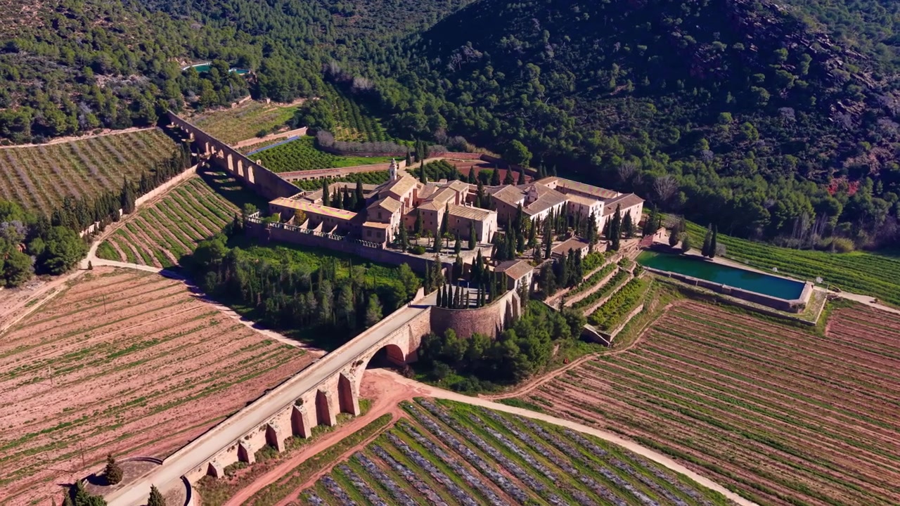 Storico monastero cistercense di Porta Coeli immerso tra vigneti terrazzati e colline boscose a Valencia, Spagna, con ponte acquedotto in pietra e bacino idrico
