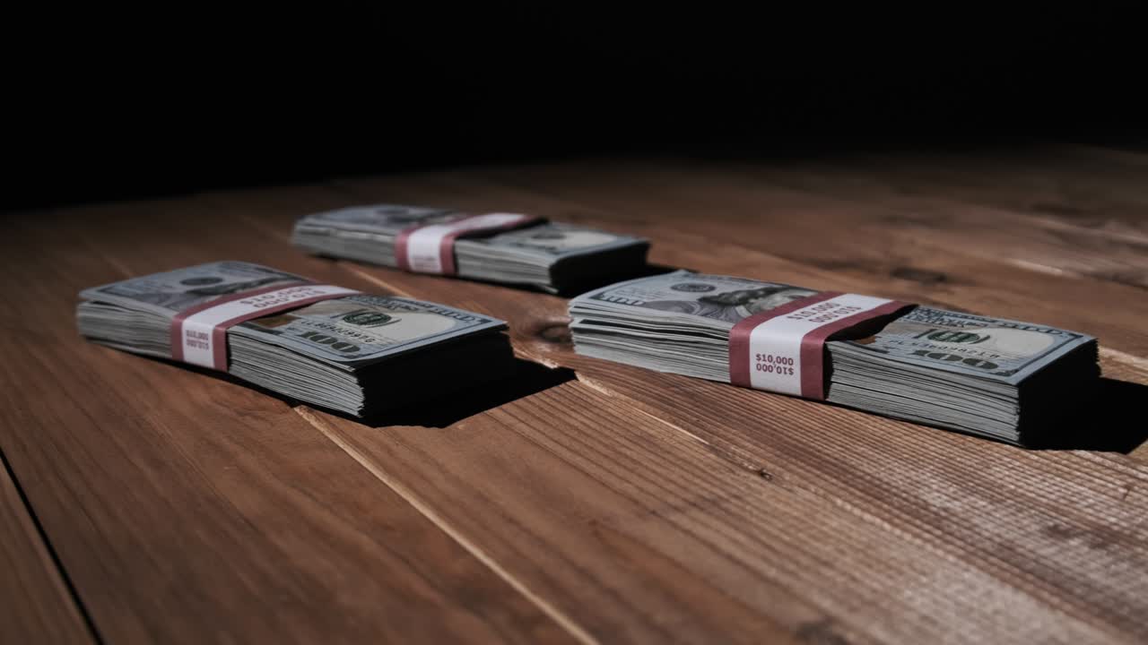 Three Stacks of 10000 American Dollars Banknotes in Bundles Lie on Wooden Table