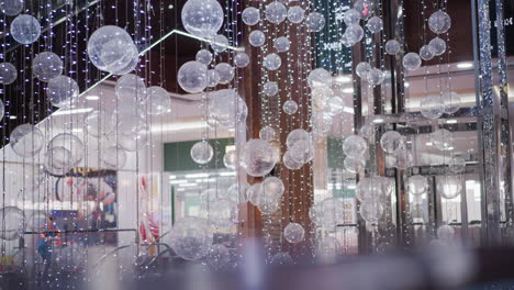 primer plano de decoración festiva brillante con esferas translúcidas suspendidas en cuerdas, creando un ambiente mágico con reflejos de luz suave, ideal para decoración de vacaciones o eventos de centros comerciales