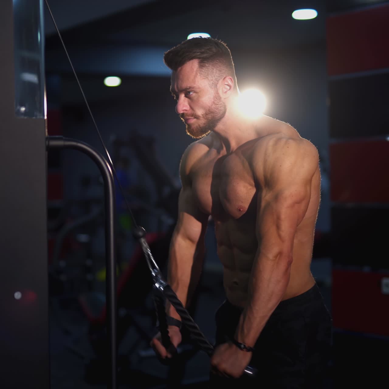 Sportivo con il busto che si allena. Uomo atletico con corpo muscoloso che si esercita vicino al simulatore nella moderna palestra. Allenamento di forza in palestra
