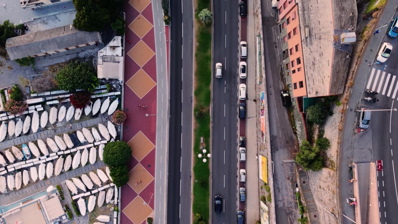Veduta aerea della strada lungomare di Genova, barche ormeggiate ed edifici colorati al tramonto.