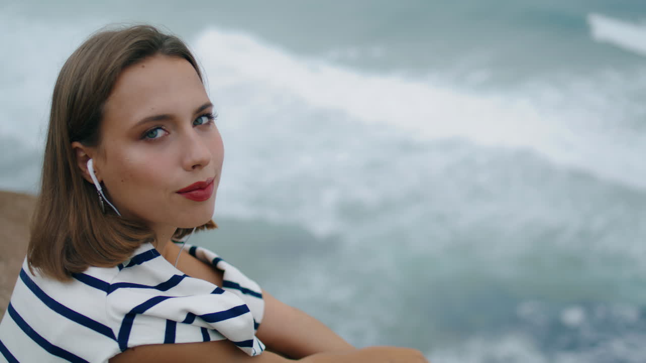 미소 짓는 밀레니얼이 오션코스트 클로즈업에서 음악을 듣고 행복한 소녀