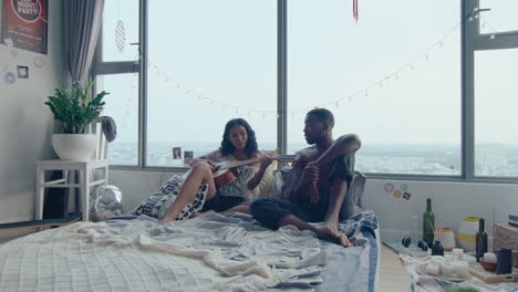 romantic couple singing and playing the guitar in bedroom