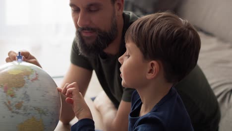 video de mano del hijo y el padre mirando el globo giratorio