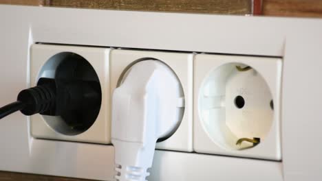 el hombre inserta cables de alimentación en el enchufe eléctrico de la pared.
