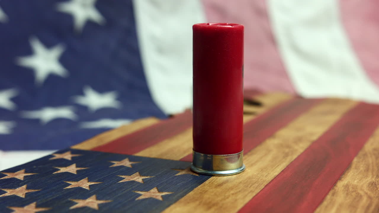 Un bossolo rosso vuoto di fucile a pompa su una bandiera americana - Primo piano.