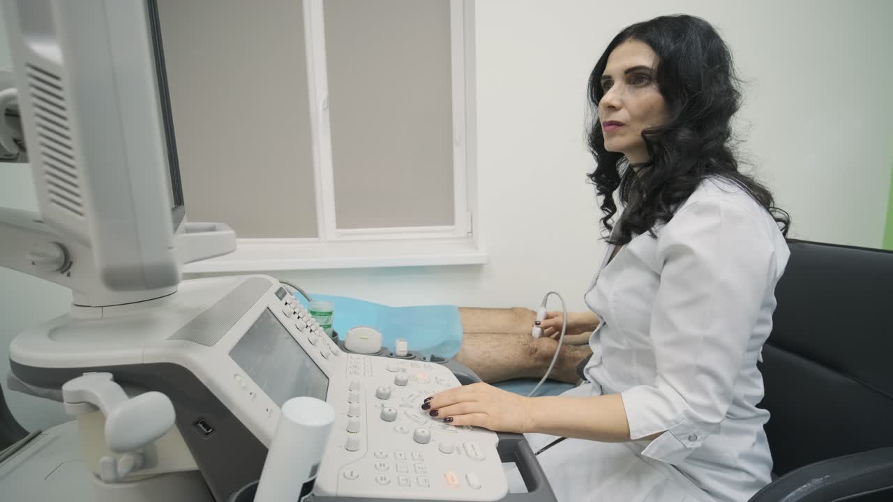 las manos de la mujer médico examinan la articulación de la rodilla del paciente joven utilizando un dispositivo de sensor de ultrasonido, sonografía. el médico ejecuta un sensor de ultrsonido sobre la pierna del paciente, la rodilla.