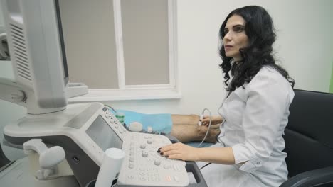 woman doctor hands examines young man patient knee-joint using ultrasound sensor device, sonography. doctor runs ultrasound sensor over patient's leg, knee.