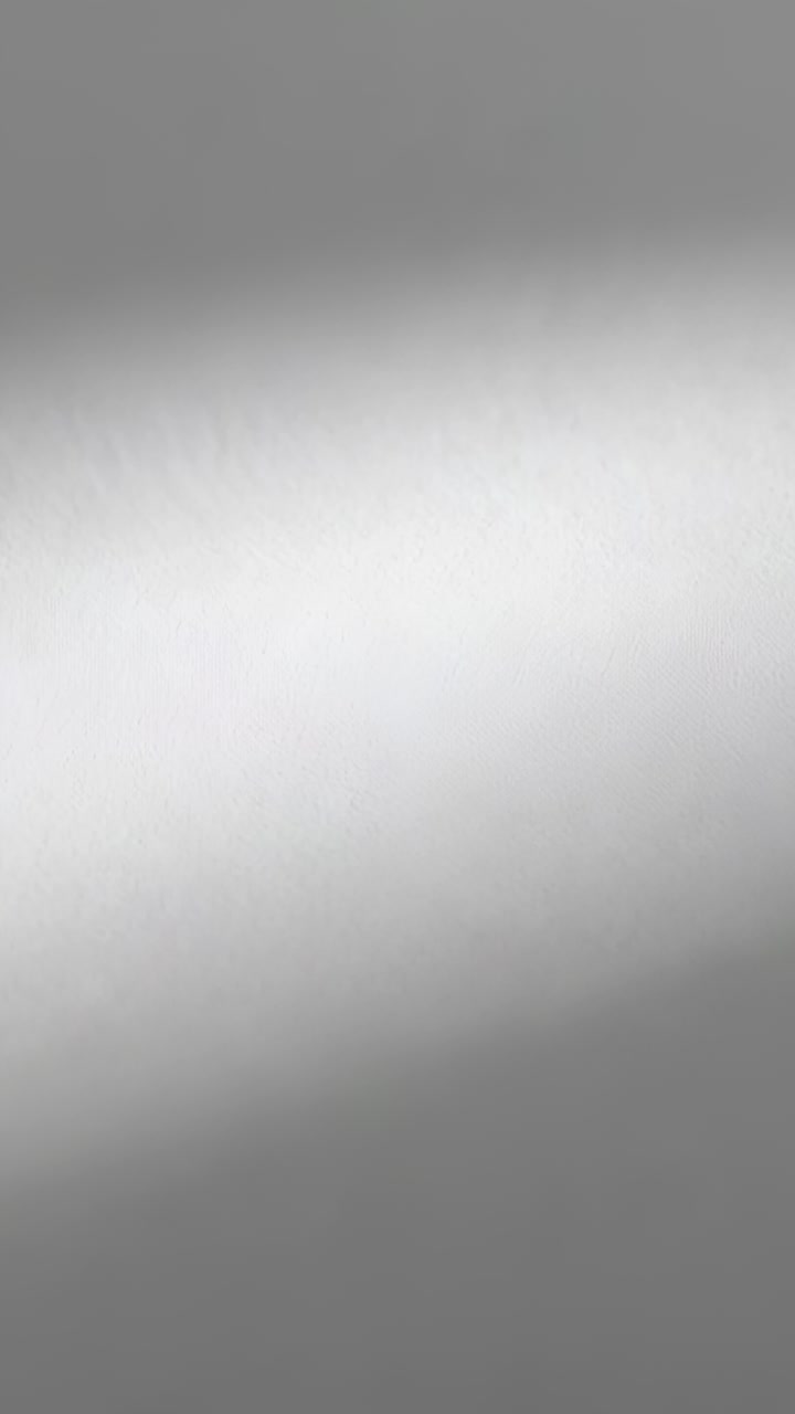 Video verticale: illuminazione e movimento della fotocamera che rivelano una leggera texture su una parete grigio chiaro