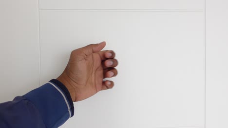 person's hand reaching towards a white wall