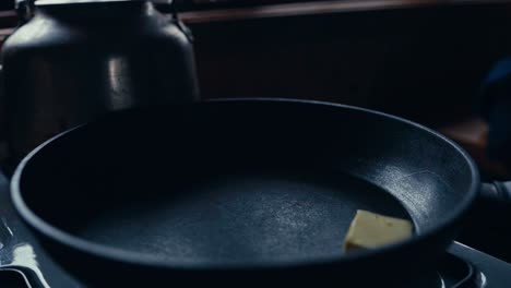 a person melting a piece of butter in a pan in a rustic kitchen at reinsjøen in åfjord, trøndelag, norway - close up