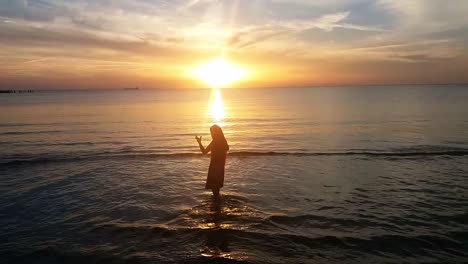 silhouette of young lady on the beach at sunset