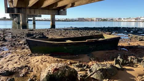 Nahaufnahme-Eines-Holzbootes-Auf-Dem-Boden-Unter-Der-Brücke,-Aufnahme-Bei-Sonnenschein,-Standort-In-Spanien