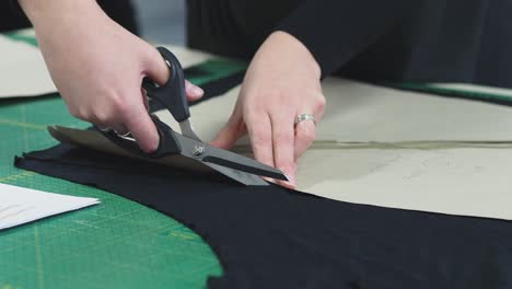 a woman cutting the fabric for a dress