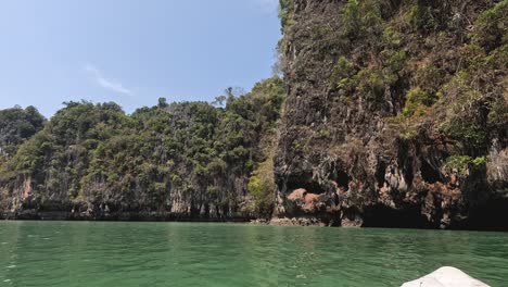 boat gliding by a lush, rocky island coastline