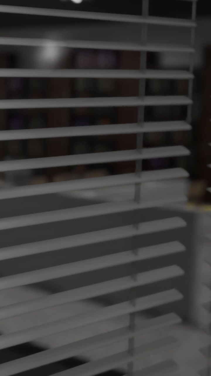 Man sits behind window blinds during daytime work session at office
