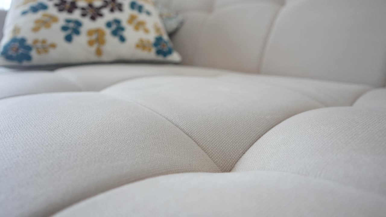Close-up of a Light-Colored Tufted Couch with a Floral Pillow