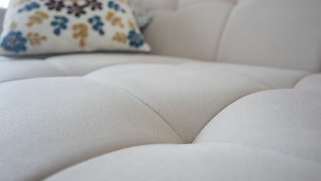 close-up of a light-colored tufted couch with a floral pillow
