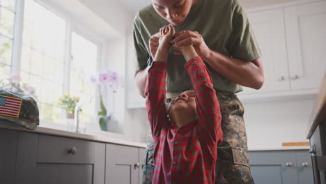 madre del ejército estadounidense en uniforme en casa de licencia jugando con su hijo en la cocina de la familia