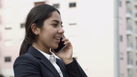 una joven mujer de negocios seria hablando por teléfono inteligente