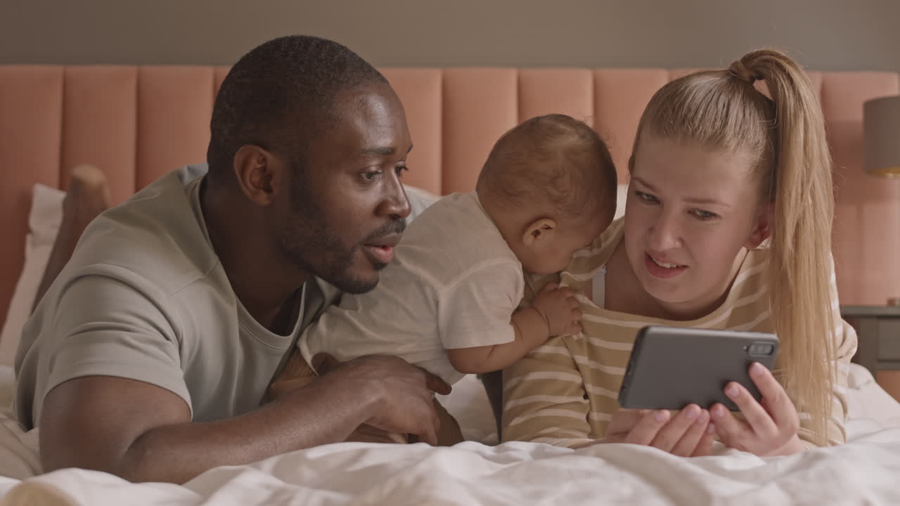 Famiglia felice a letto con smartphone