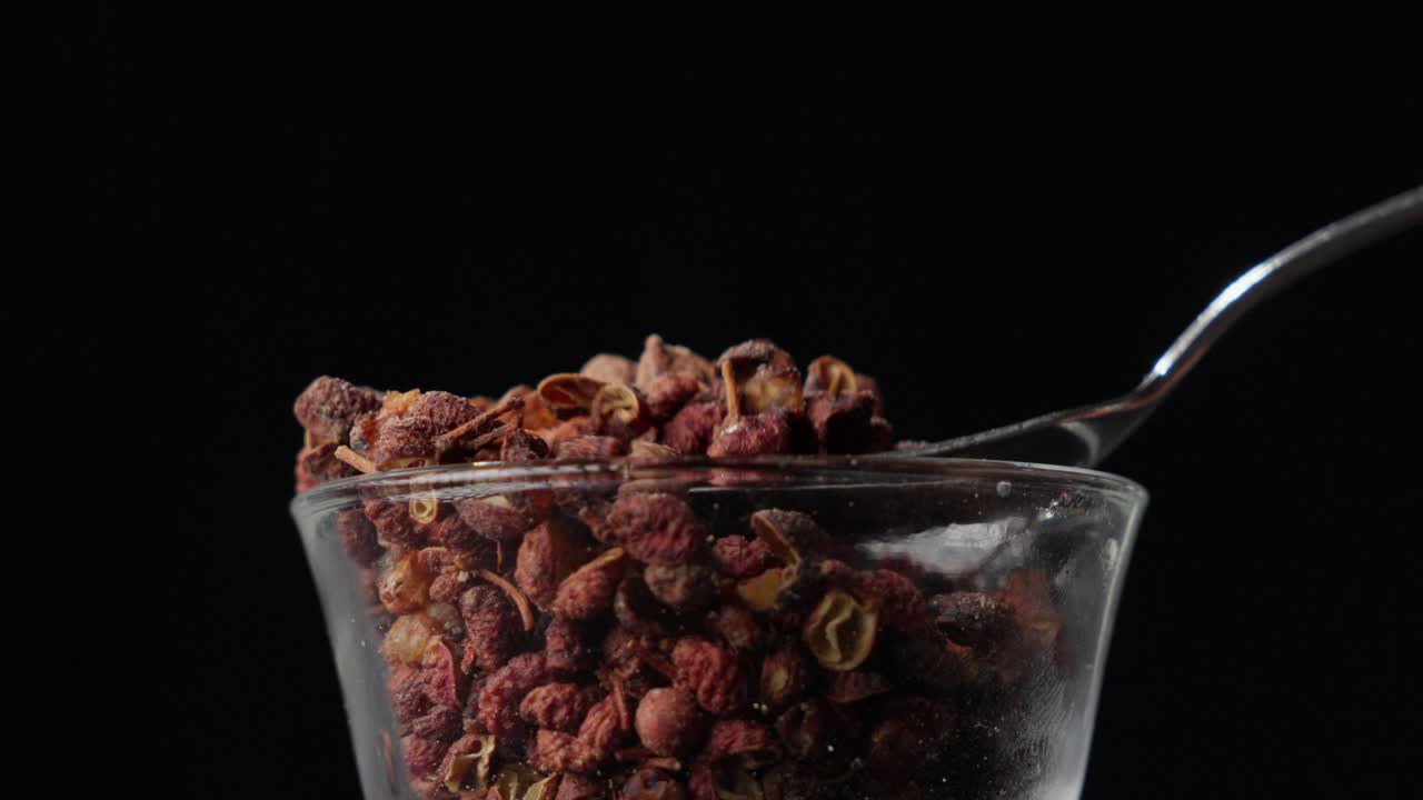 Spoonful of fresh raw spicy pepper, glass beaker, silver utensil, slow-mo