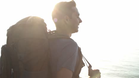 happy male backpacker standing at rocky cliff