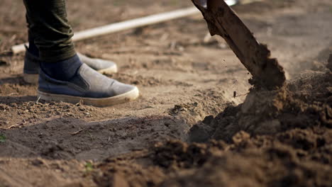 preparation of soil for the planting season in spring. unrecognized farmer using shovel to dig the ground.