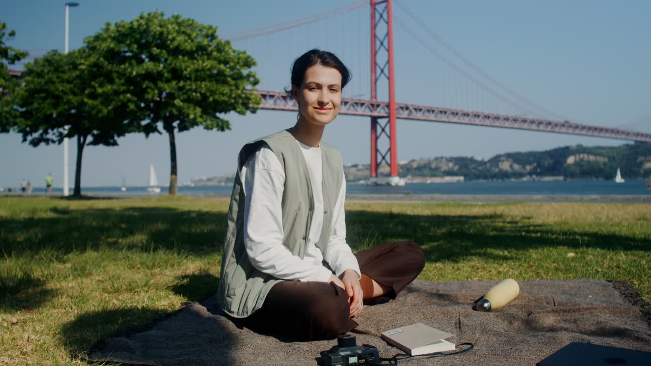 다리의 전망 을 가진 공원 에서 피크닉 을 하고 있는 여자