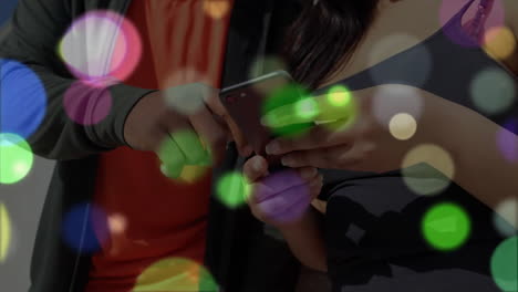 using smartphone, people with colorful bokeh lights animation in background