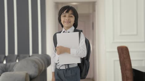 retrato de un niño de escuela indio feliz de pie con libros