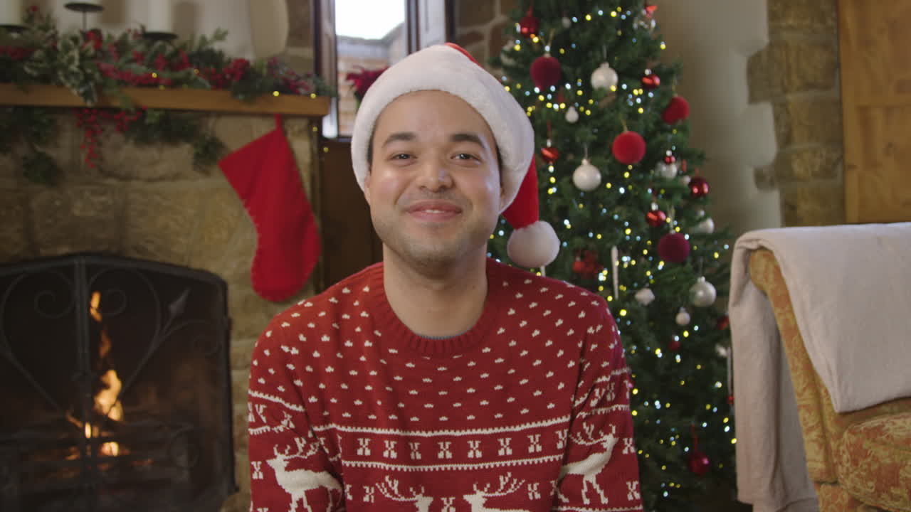 joven levantando una copa de champán y hablando con la cámara durante una videollamada navideña