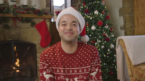 young man raising glass of champagne and talking to camera during a christmas video call