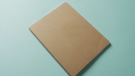 close up of closed brown book with copy space on green background in slow motion