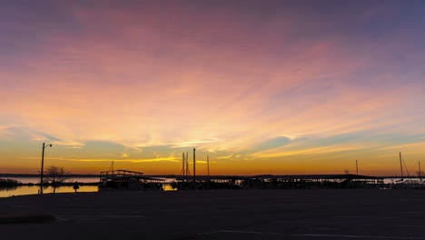 person walks to boat house at early morning, sun rises and shines rays between ship masts