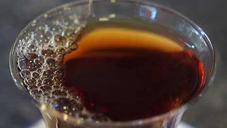 close-up of a glass of black tea with bubbles