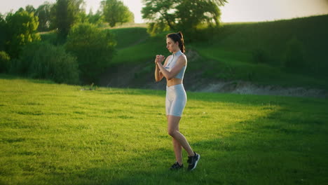 Una-Mujer-Se-Balancea-Parada-Sobre-Una-Pierna-Y-Se-Inclina-Hacia-Adelante-En-Un-Parque-En-El-Verano-Al-Atardecer