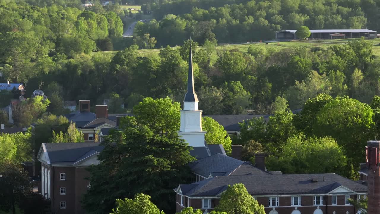 Church tower of Sweet Briar College School in Lynchburg, VA. Aerial orbit shot. Sunny day with green trees in spring season. Wide shot. Historic campus buildings in USA.