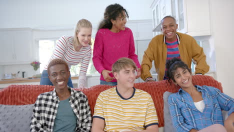 happy diverse group of teenage friends sitting on couch and laughing at home, slow motion